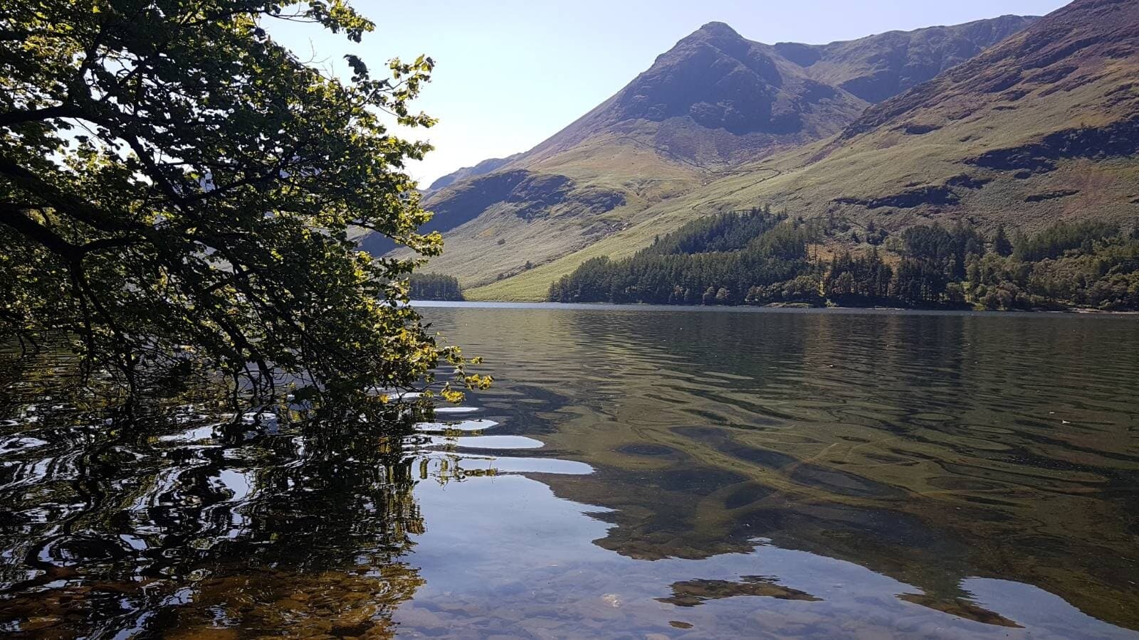 Peaceful lakeside mountain scenery with calm water and lush greenery, ideal for resilience and mental wellness.